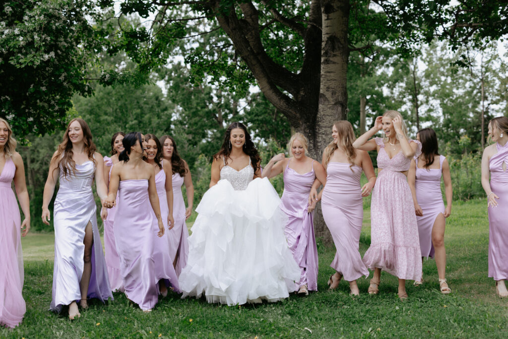 A group of ladies walking together while standing next to a tree. 