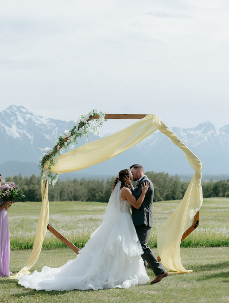 Couple sharing a kiss with one another during their backyard wedding in Alaska. 