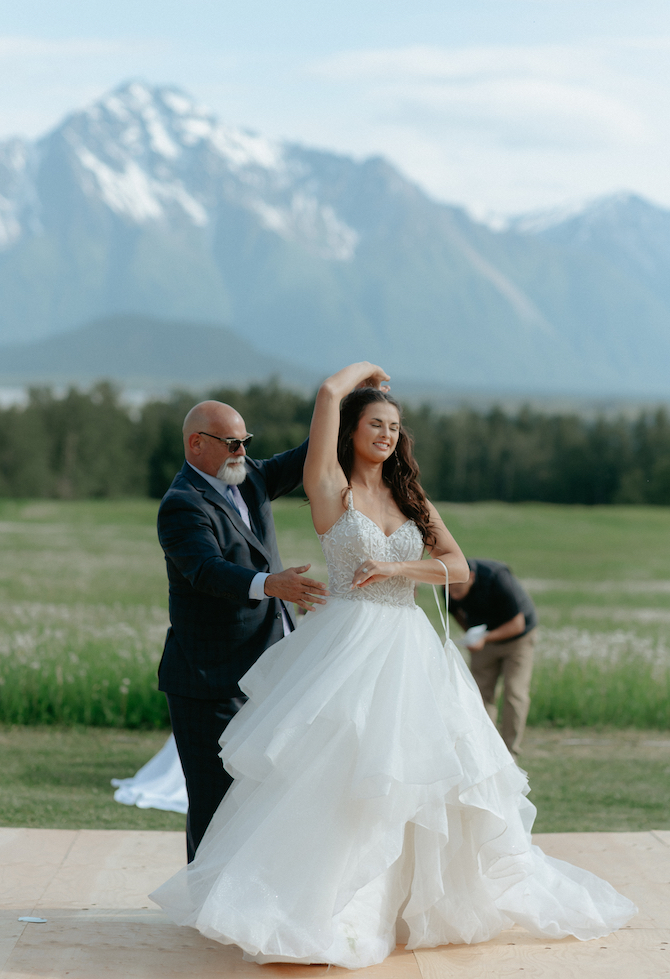 Father of the bride and bride dancing together on an outside dance floor in Alaska.