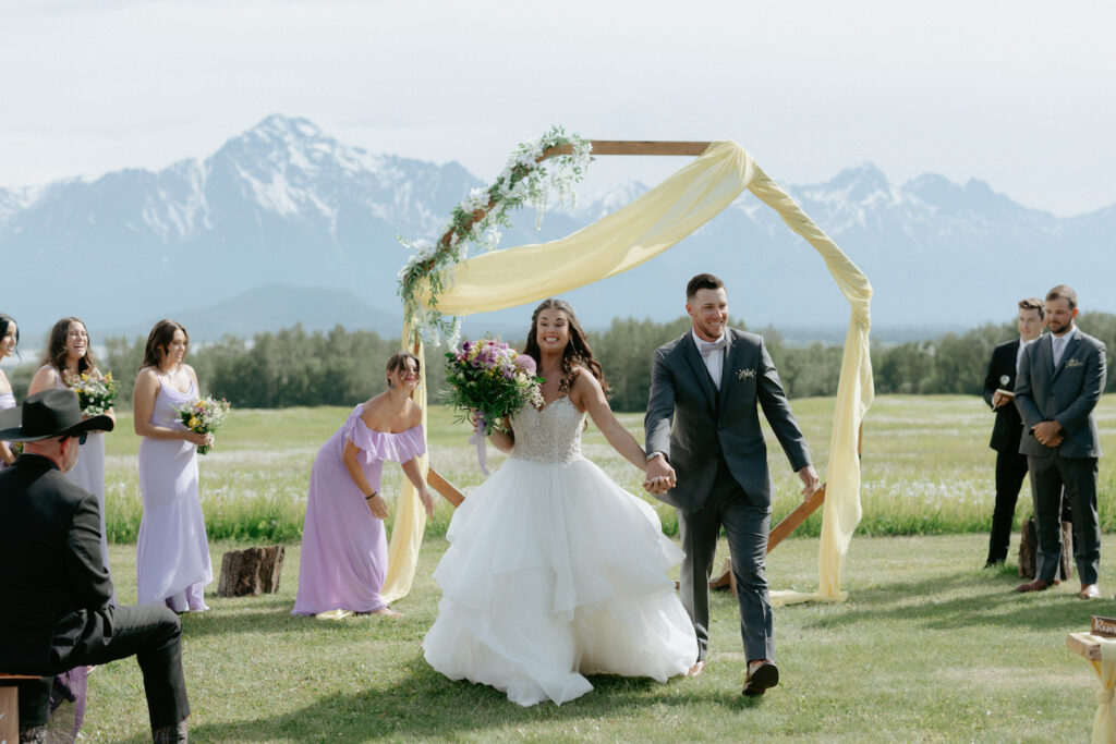 Couple walking back down the aisle and holding hands during a wedding.