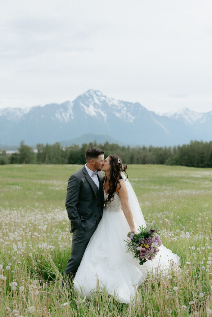 Couple kissing in a field of flowers in Alaska during their wedding.