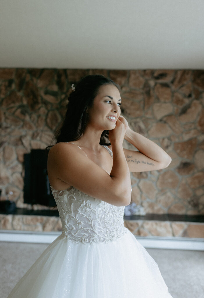 Woman wearing a wedding dress standing in front of a window inside a home in Alaska