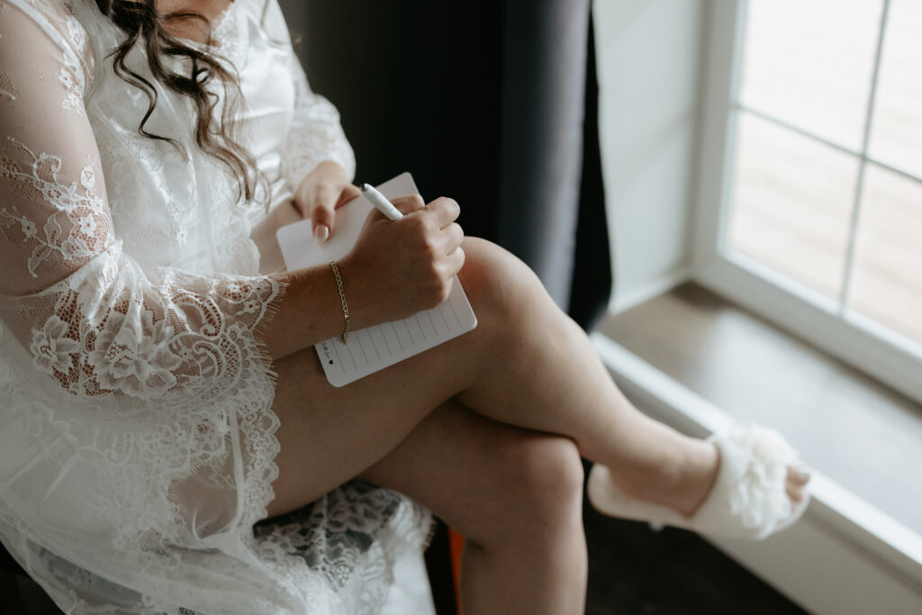 Women writing with a white pen inside a vow book. 