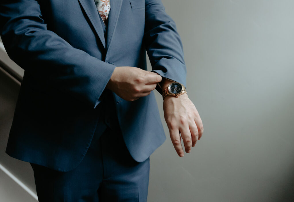 Man moving his sleeve to show his blue watch face. 