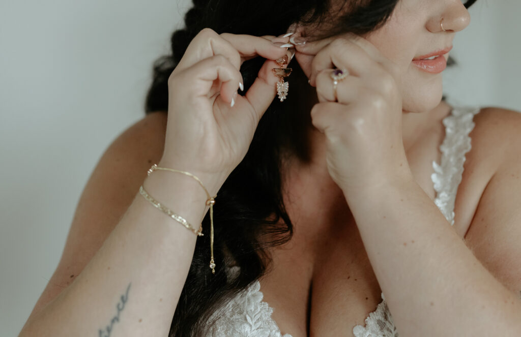 Woman touching her earlobes while putting in earrings.