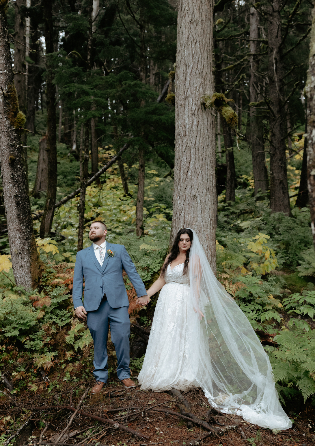 Couple standing in a forrest in Girdwood, Alaska. After having a rooftop mountain wedding ceremony.