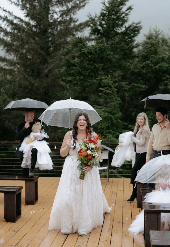 Woman walking while holding a colorful bouquet and umbrella on a deck.