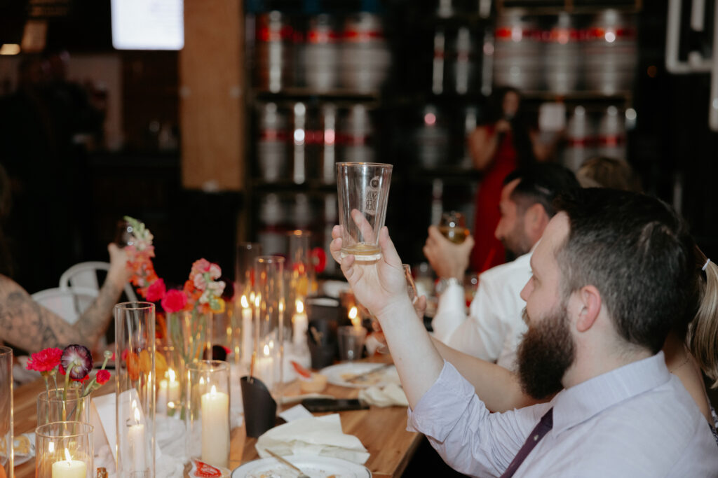 A man holding up a beer glass during toasts. 