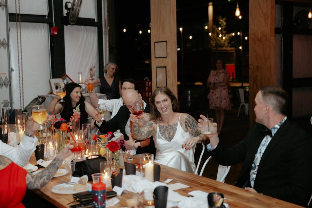 A group of people sitting at a table and holding up their glasses. 