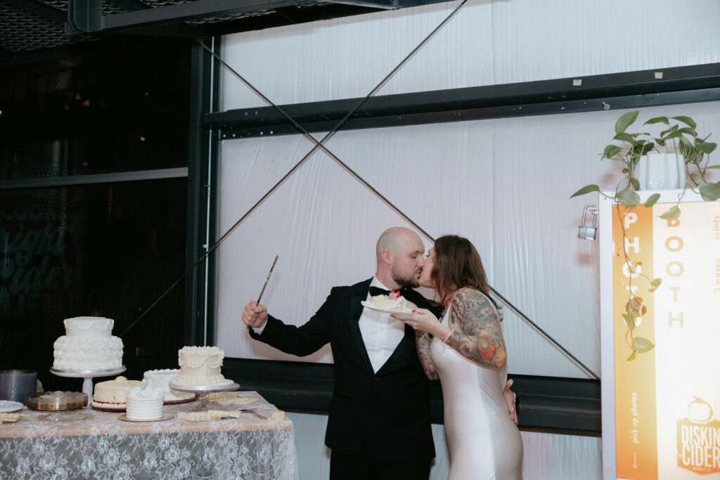 A couple kissing while cutting the cake. 