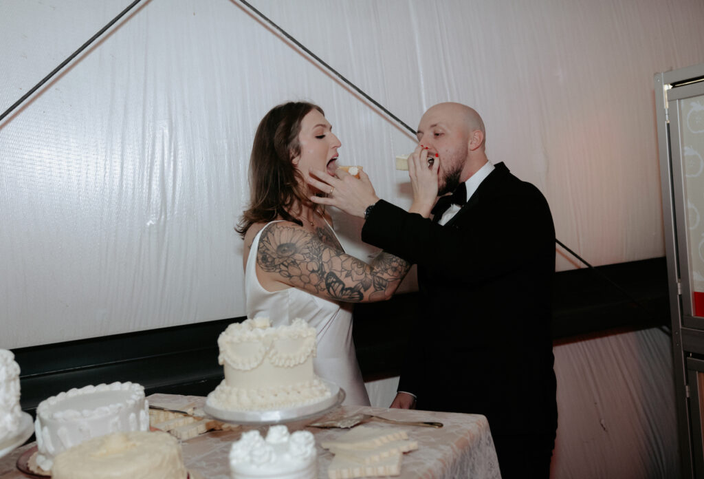 A couple feeding one another a piece of white cake. 