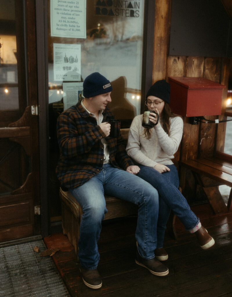 A couple sipping on their drinks outside a aframe style coffee shop. 