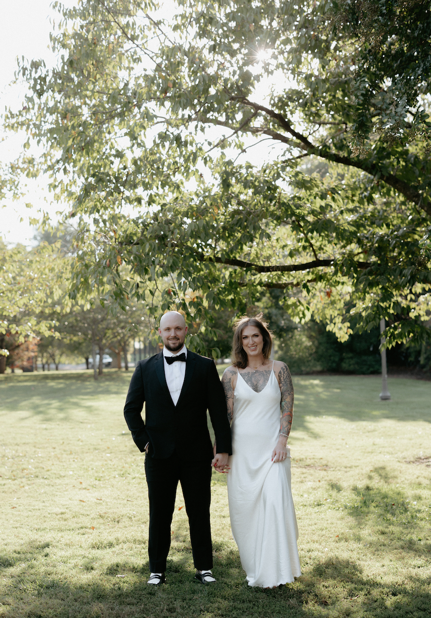 A couple holding hands while standing under a tree.