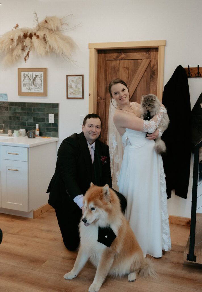 A couple standing together while holding their pets. 