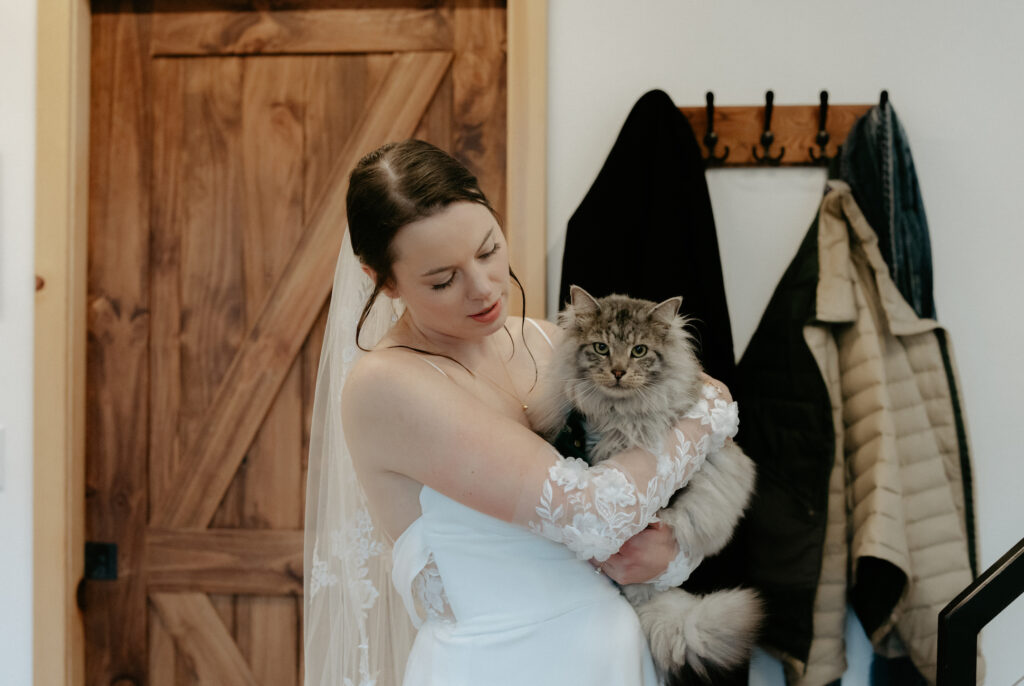 Woman holding onto a cat while wearing a white dress.