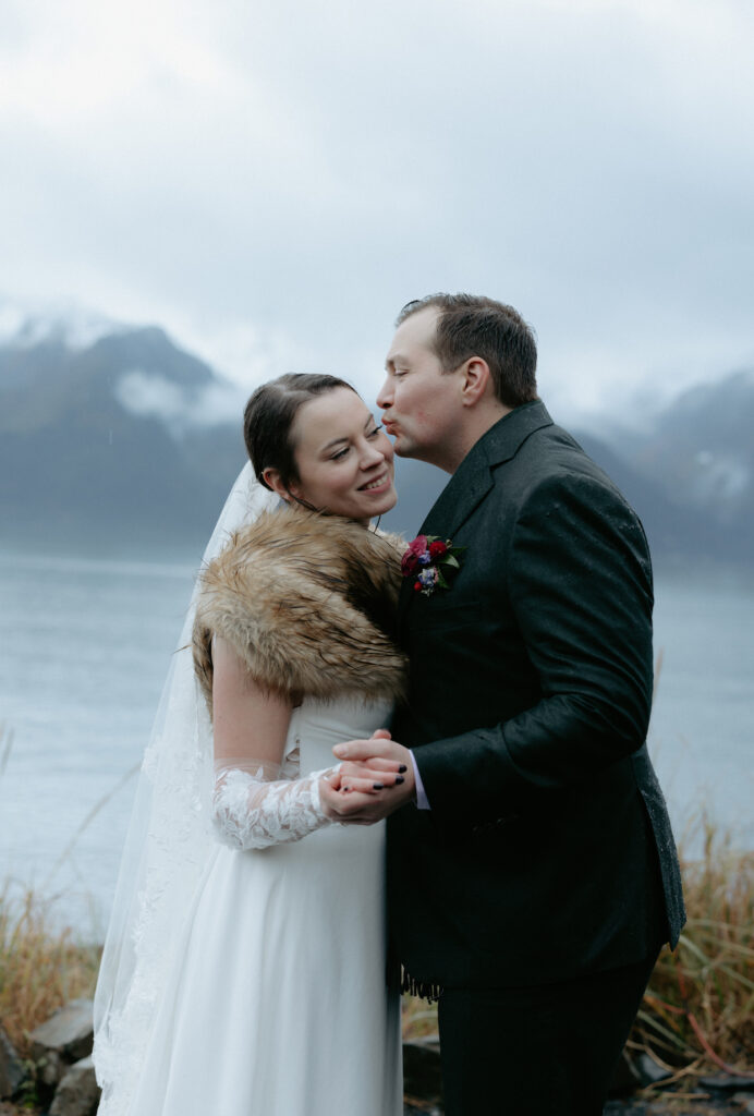 Man kissing woman's cheek next to a mountain. 