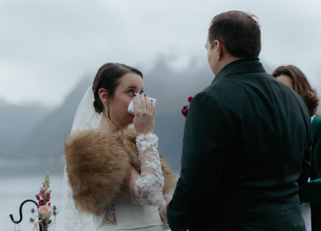 Woman using a white tissue to wipe away a tear. 