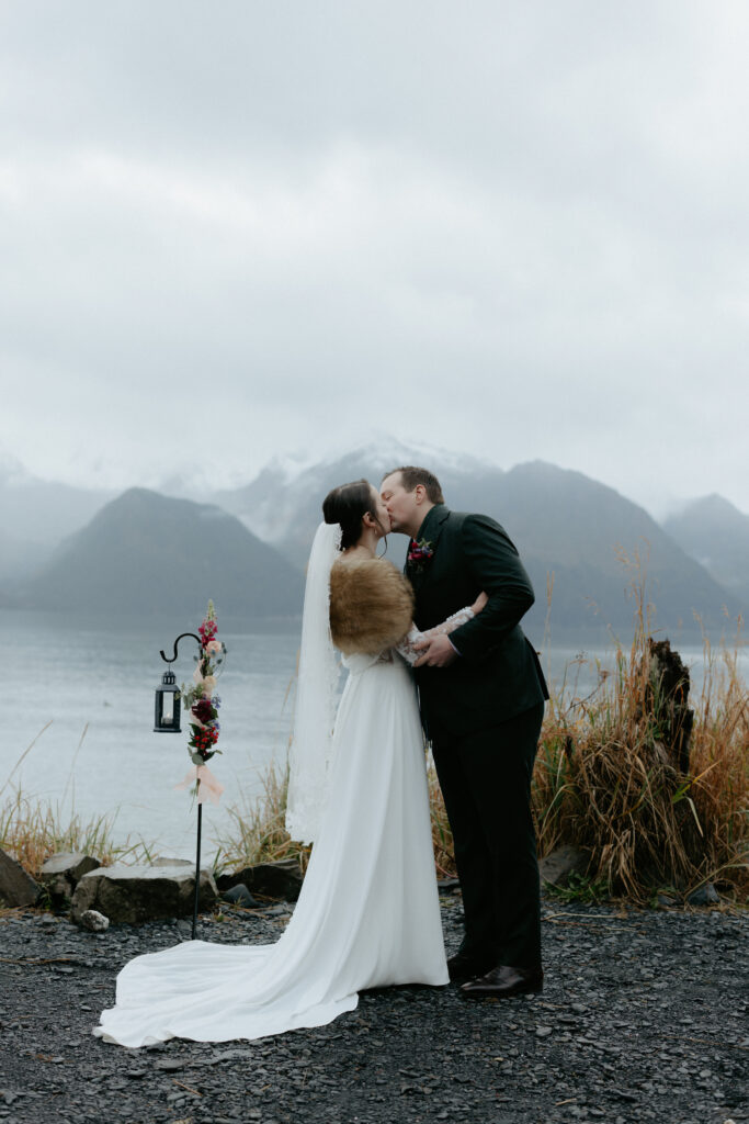 Couple kissing while standing next to the ocean. 