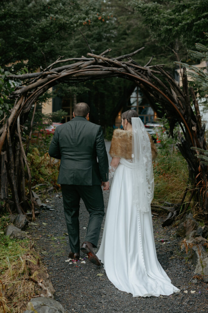 Couple walking through a round wooden arch. 