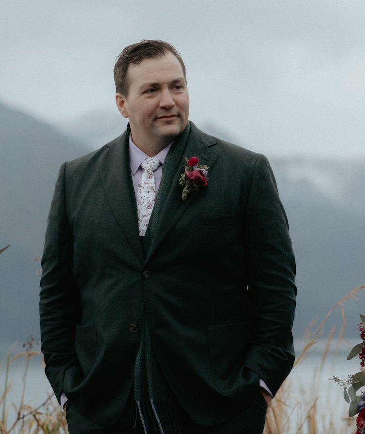 A man standing wearing a green suit.