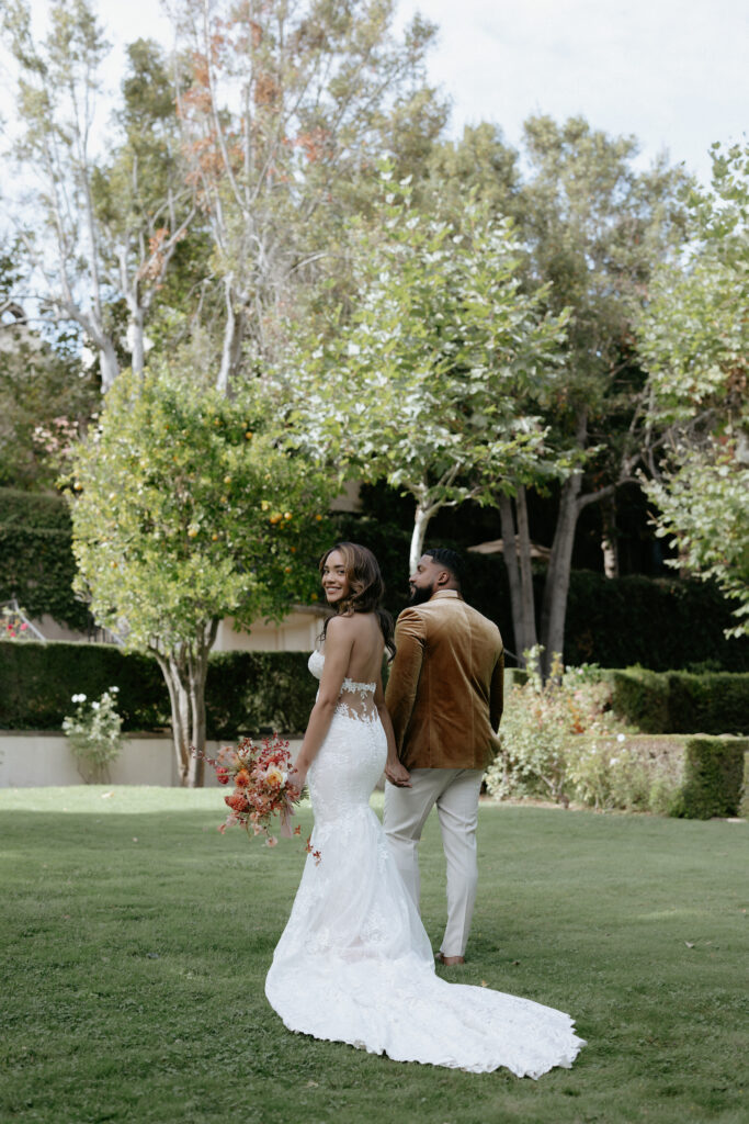 A woman looking over her shoulder while holding a bouquet and wearing a white dress.