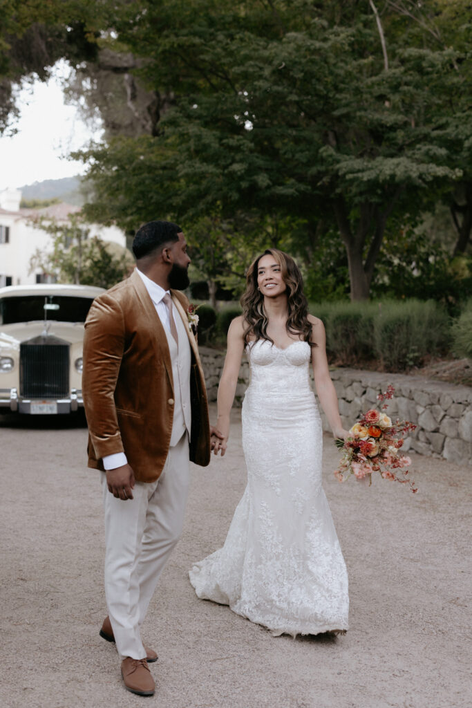 A couple walking away from a vintage styled car. 