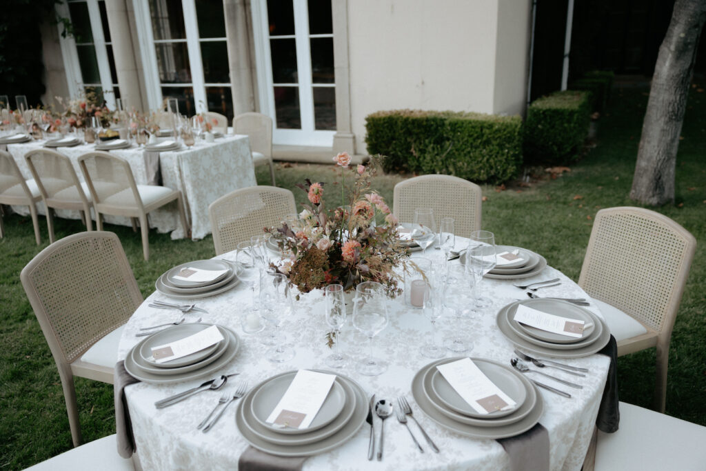 A round table with 8 sets of grey plates and a floral arrangement in the center. 