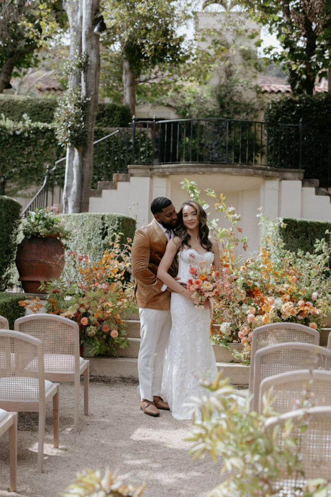 A couple standing with one another at the front of a wedding ceremony site. 