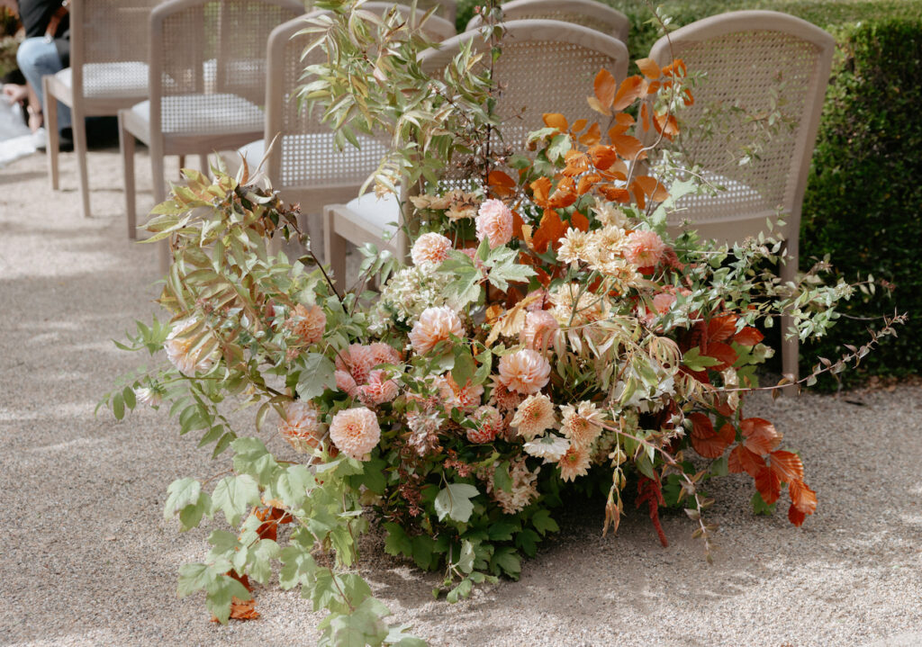 Orange and pink florals setup behind a set of chairs. 