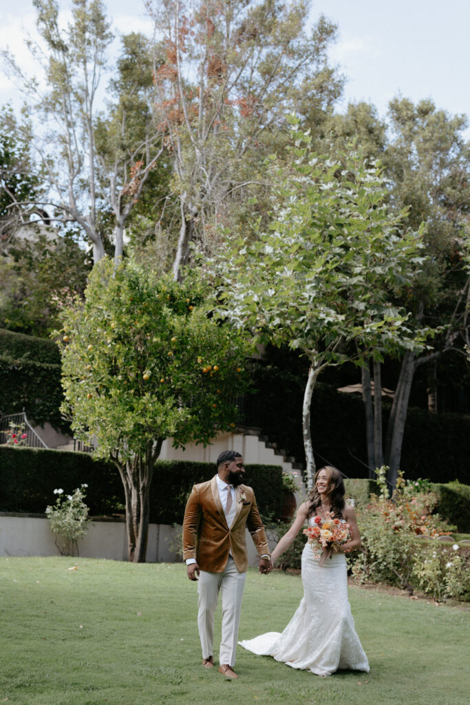 A couple holding hands and laughing as the walk through a large courtyard space. 