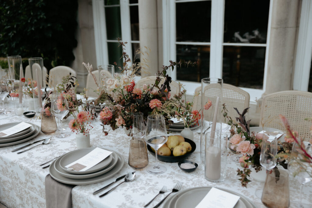 A vibrant bunch of florals placed on a table next to a dish with pears in it.