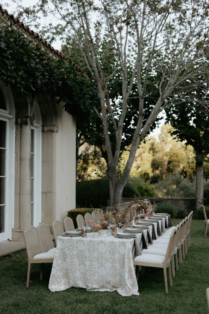 A fully set up wedding tables setting underneath a tree in front of the venue. 