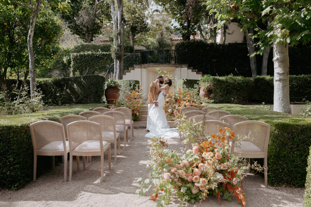 A couple kissing in front of their ceremony setup. 