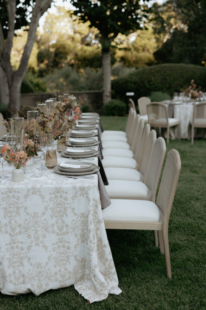 A row of chairs with white seats tucked under a table. 