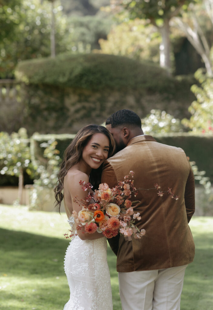 A woman holding a large bouquet of flowers while snuggled into a man's arm.