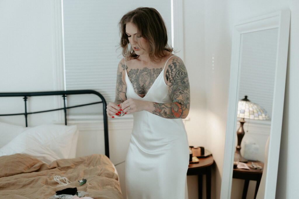 A woman picking up pieces of jewelry and getting ready to put them on. 