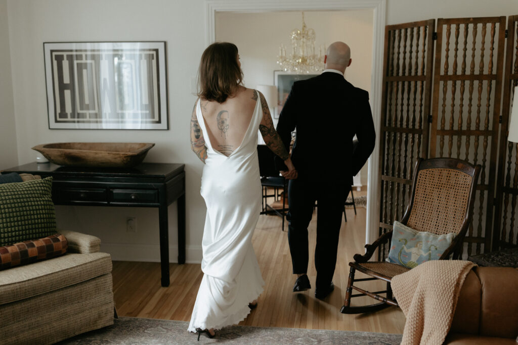 A man holding a woman's hand and leading her through a door frame. 