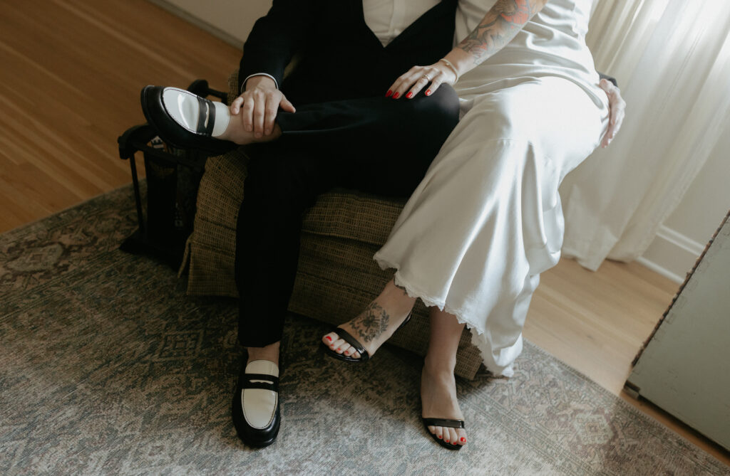 A couple in wedding attire sitting on each other in a chair. 