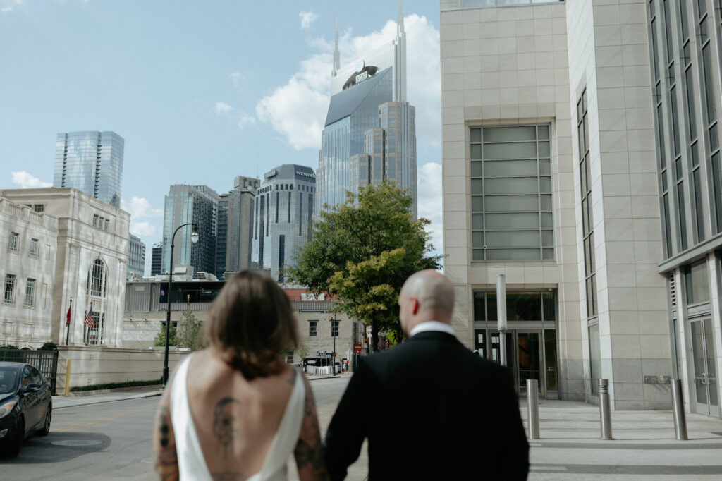 A couple holding hands and walking toward the skyline. 