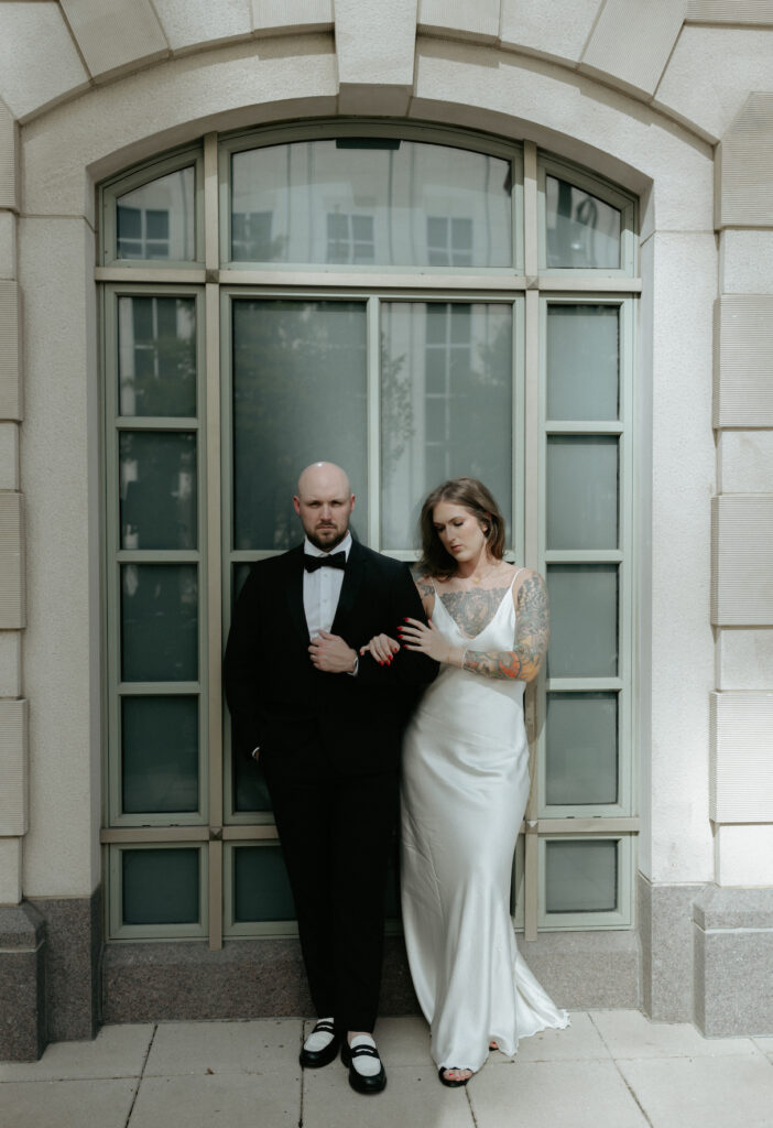 A couple standing in front of a blue window at the. 