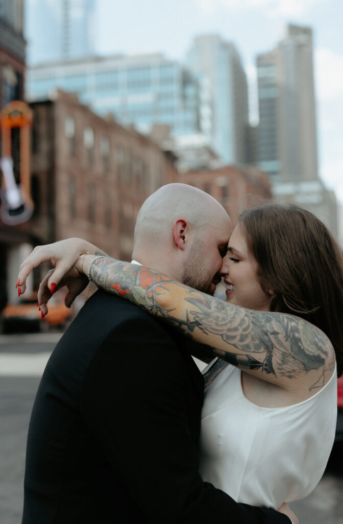 A couple embracing one another with the skyline behind them. 