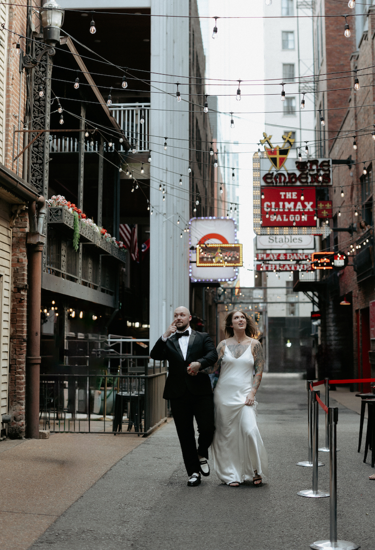 A couple holding hands and walking through an alley. 