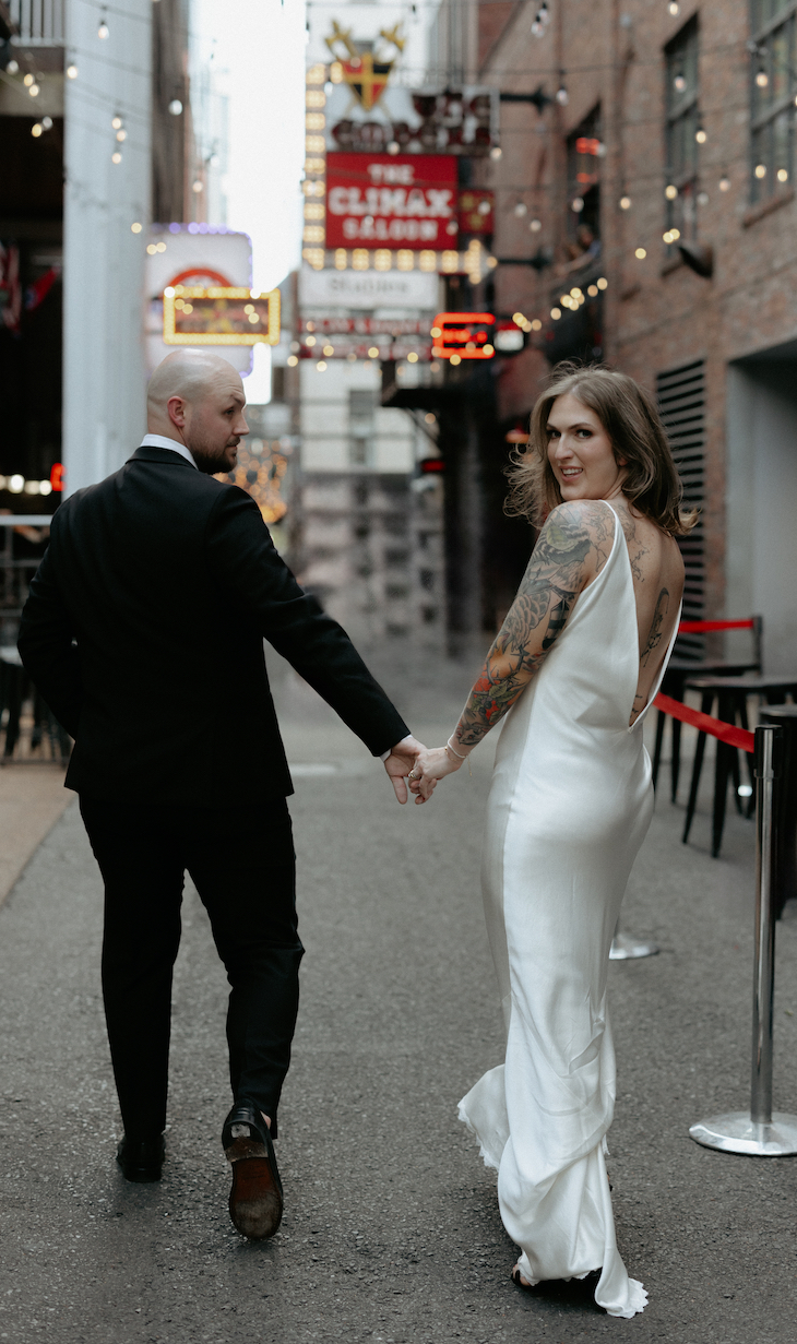 A woman looking over her shoulder while holding a man's hand. 