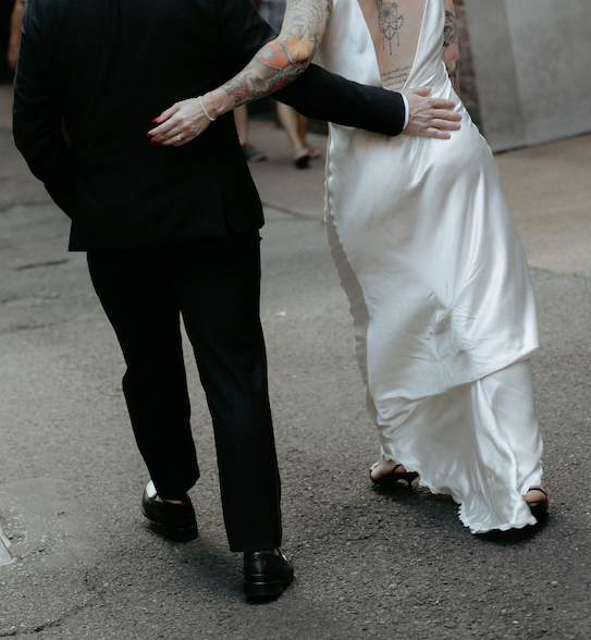 A couple holding onto one another while walking through printers alley.