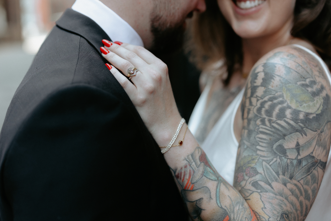 A woman's hand with red nails and ring wrapped on a maps shoulder. 