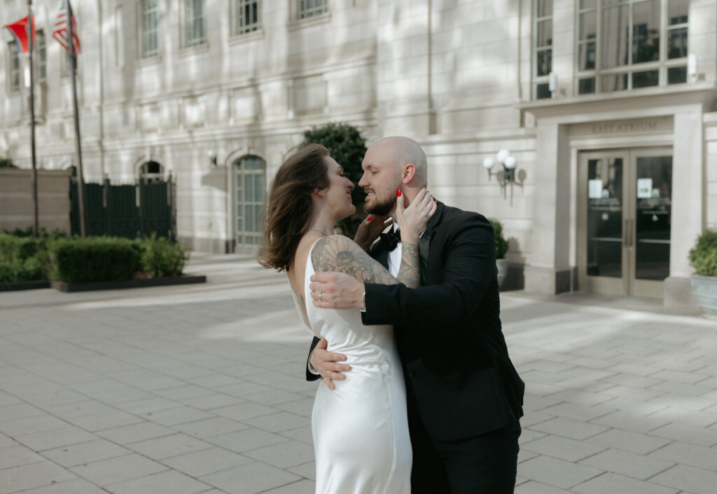 A couple embracing in front of the symphony building. 