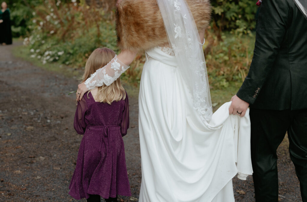 Couple walking together with a girl wearing a purple dress. 