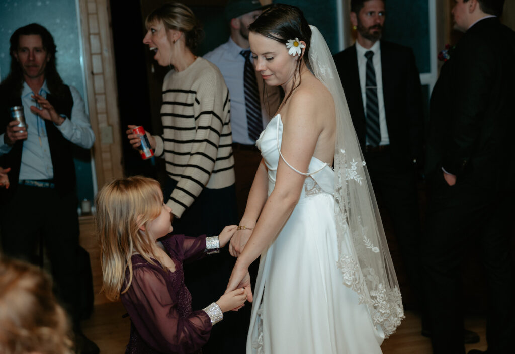 Woman wearing a white dress dancing with a little girl. 