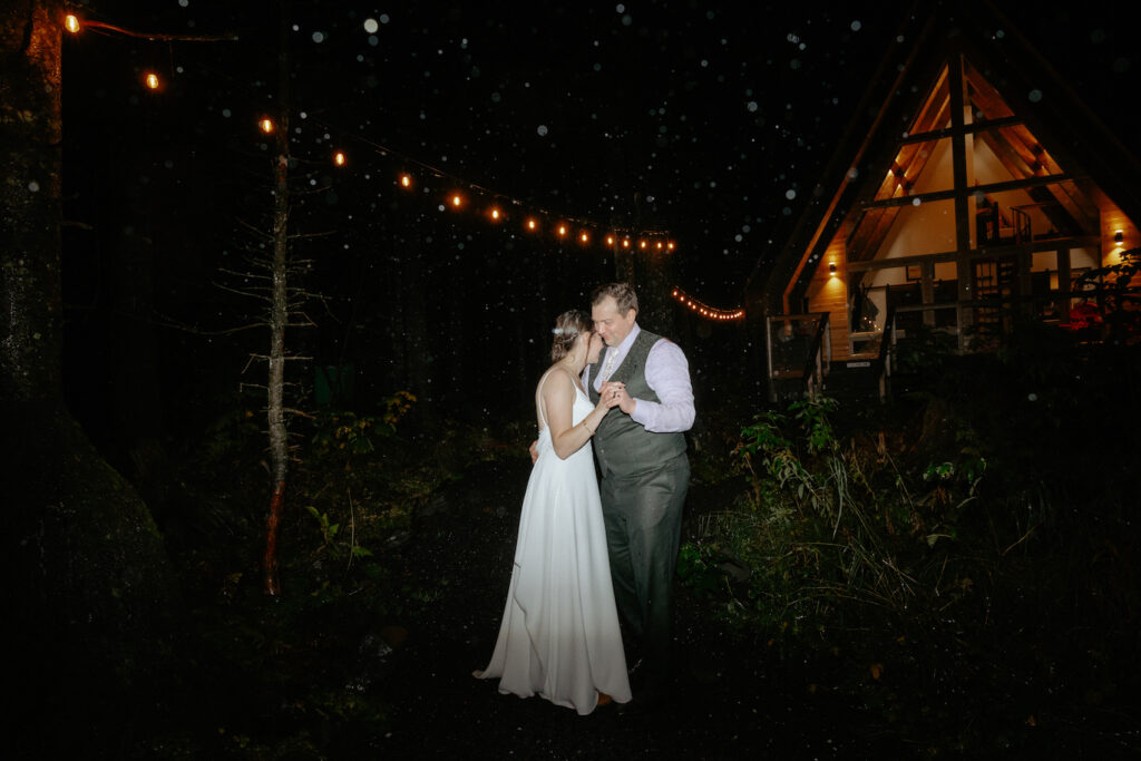 Couple standing under twinkly lights in the rain.