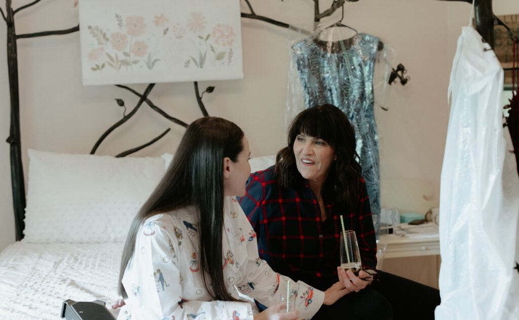 A woman holding onto another woman while sitting on a bed. 